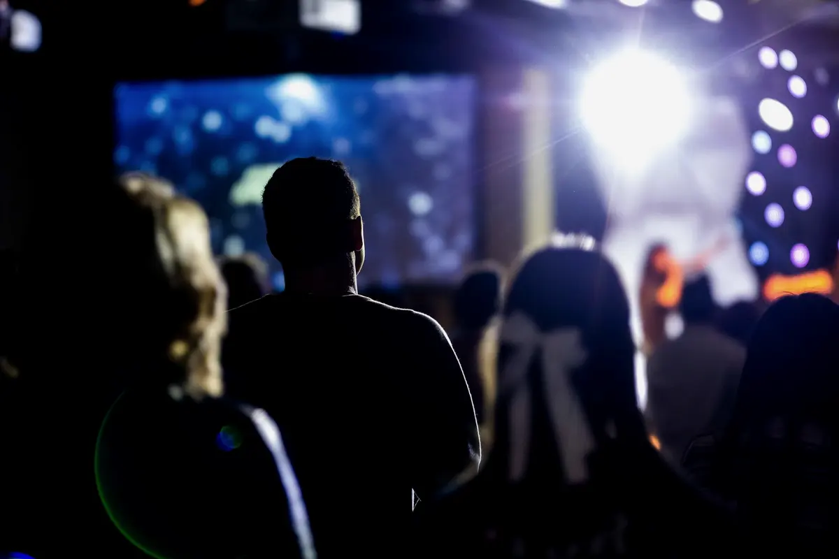 An audience in silhouette facing a brightly lit stage.