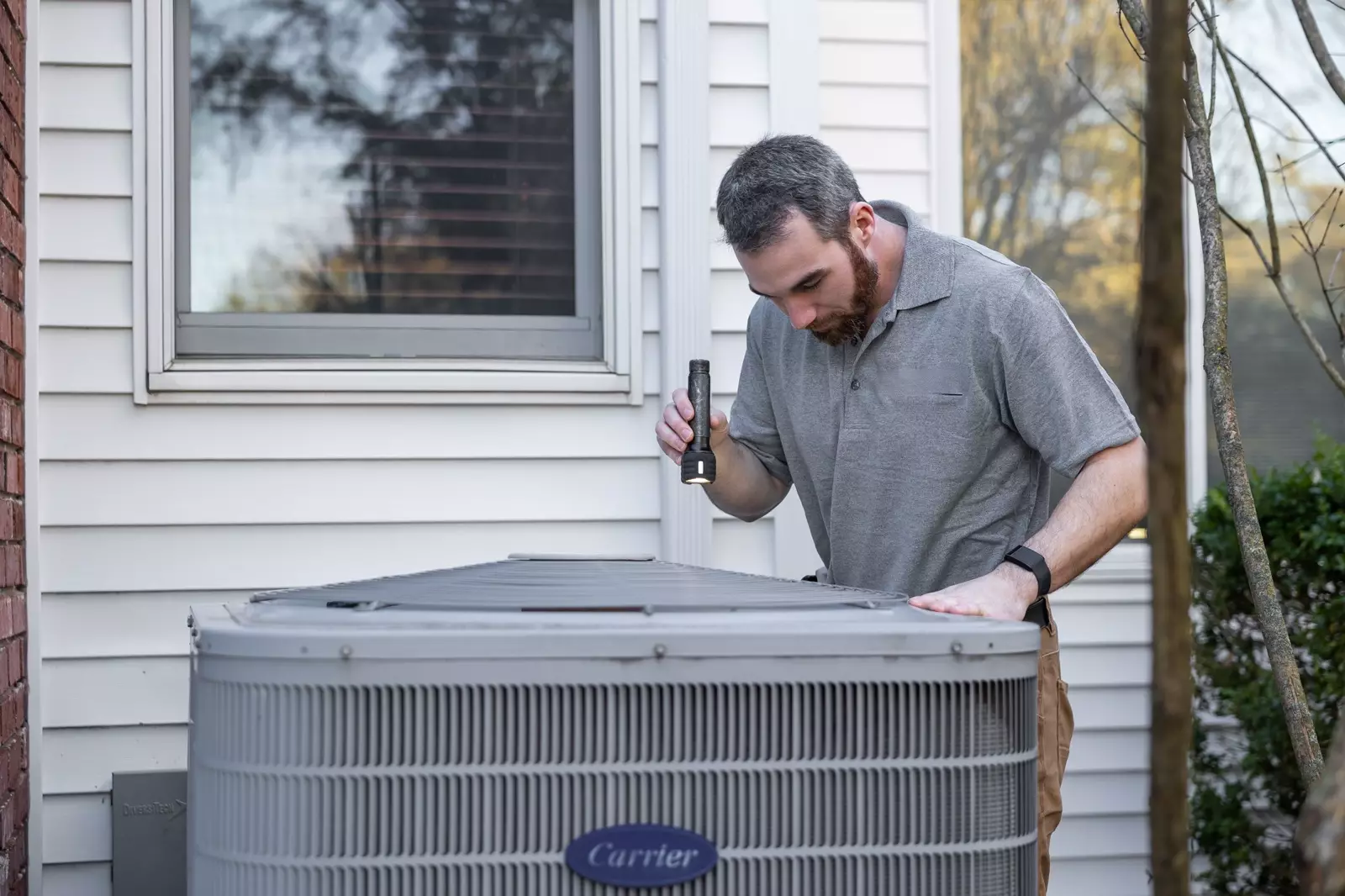 A technician inspecting an outdoor air-conditioning unit